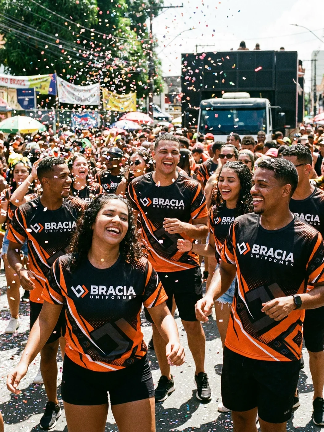 Amigos dançando num bloco de rua com confete, vestindo o abadá preto e laranja da Bracia